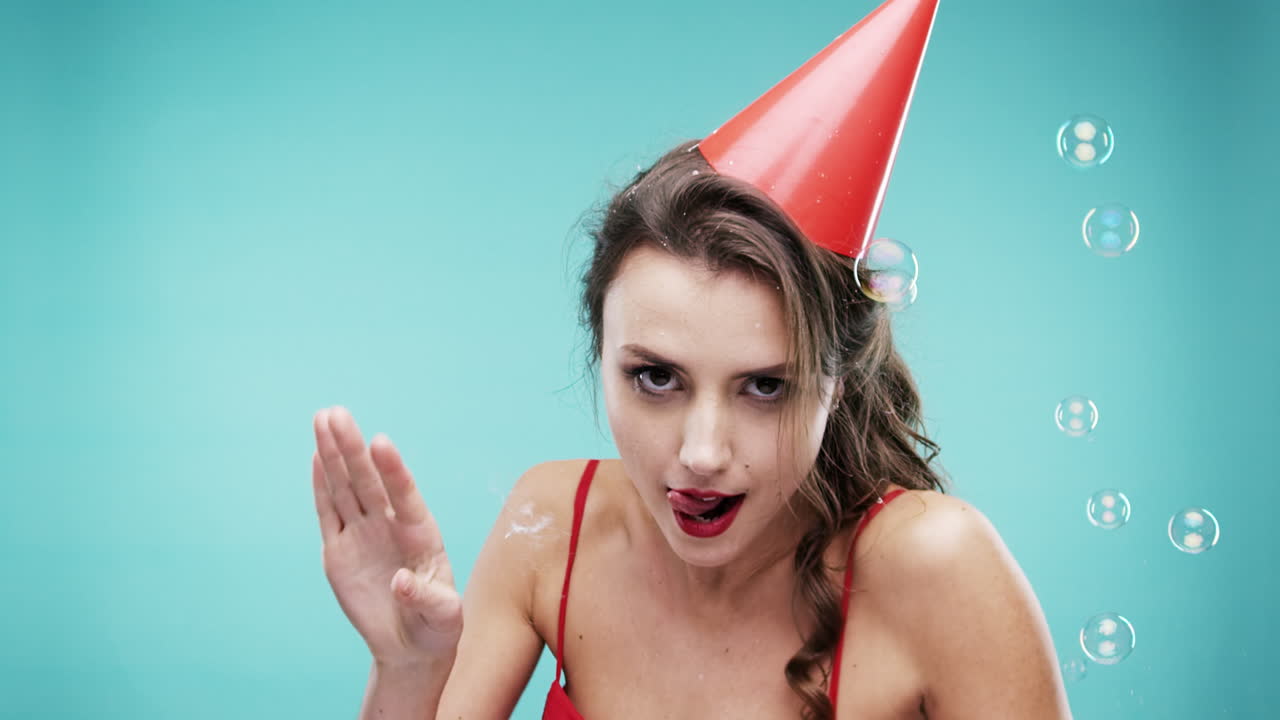 파티 모자와 거품을 입은 빨간 드레스를 입은 여자