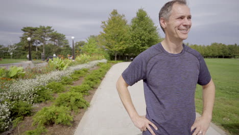 man exercising in park stops to smile and look to horizon