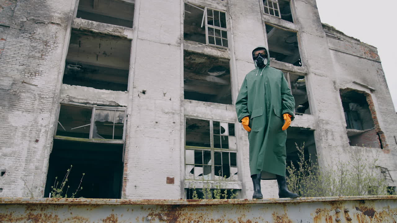 Person in protective suit standing in ruined city. Man in biohazard suit.