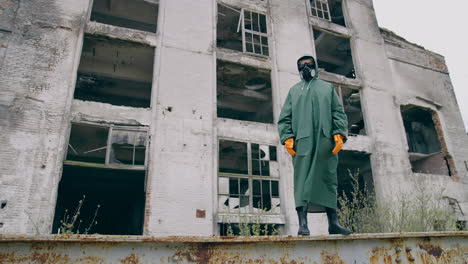 person in protective suit standing in ruined city. man in biohazard suit.