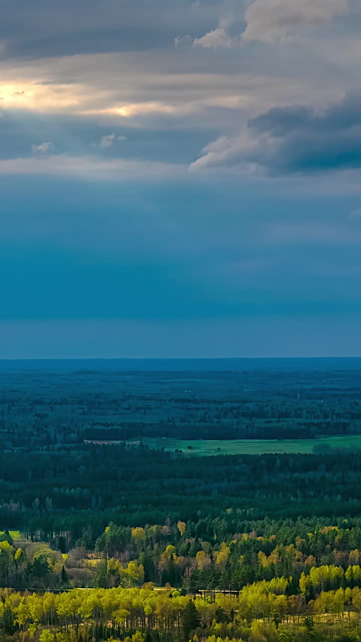 Dark blue clouds drift swiftly across the sky in a time-lapse above a quiet landscape