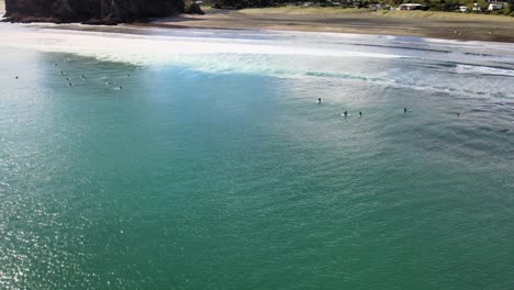 Surfistas-Esperando-El-Próximo-Set-En-La-Playa-De-Arena-Negra-De-Piha