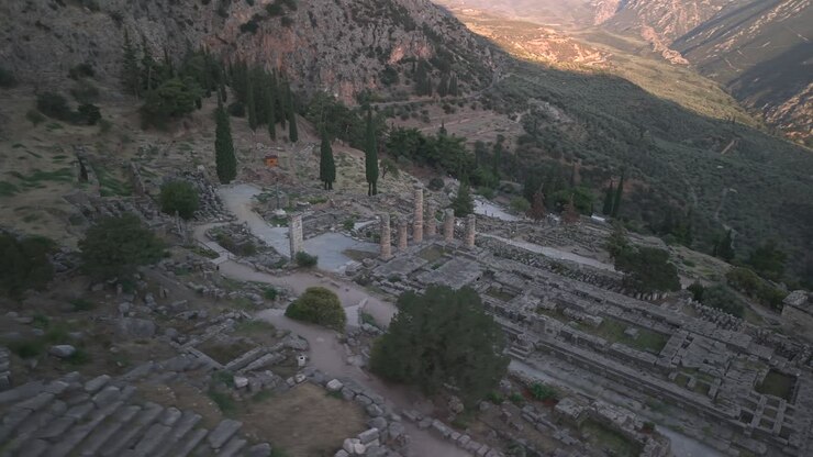 Ripresa aerea circolare con drone intorno alle rovine del Tempio di Apollo a Delfi, Grecia, al tramonto, che mostra l'antico sito archeologico.