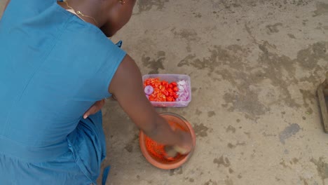 Frauenhände-Mahlen-In-Ghana-Chilischoten-Und-Violette-Zwiebeln-Mit-Einem-Mörser,-Um-Soße,-Eine-Beilage-Zu-Banku,-Zuzubereiten