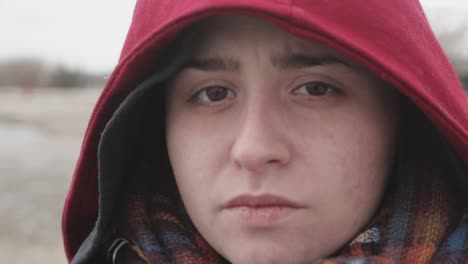 an anxious facial expression of a young lady wearing a red hoodie jacket - close up shot