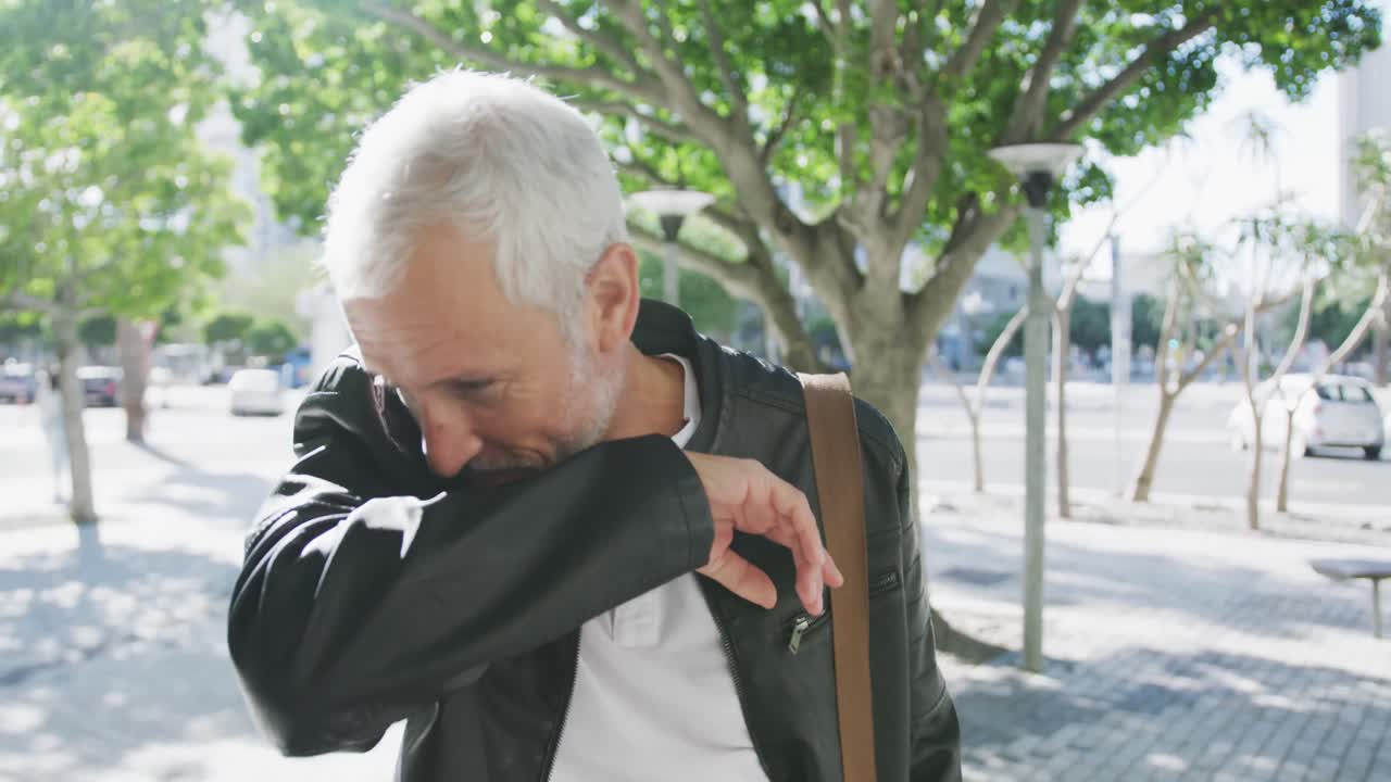 코카시안 남자가 도시 거리에서 재채기 할 때 입을  ⁇ 고 있습니다.