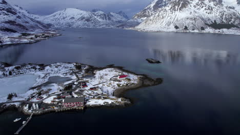 aerial flyover sildpollnes church with scenery winter landscape in background, snow covered mountains, lofoten norway