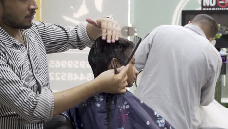 young boy getting haircut at barbershop