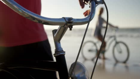hombre de pie con su bicicleta en la playa
