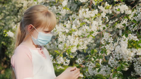 niño triste con una máscara cerca de un problema de alergia a los árboles en flor