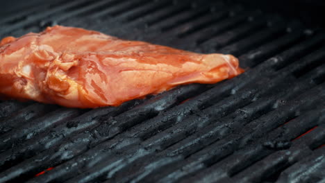 Placing-a-marinaded-chickenbreast-on-a-gas-grill