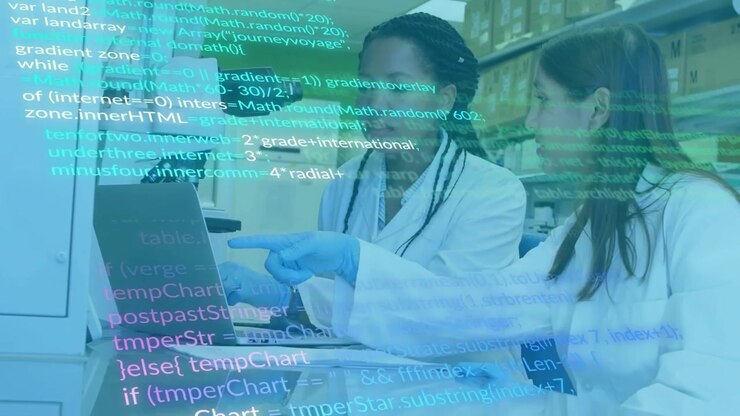 Two researchers pointing at laptop in lab, reviewing data as code overlay scrolling across screen