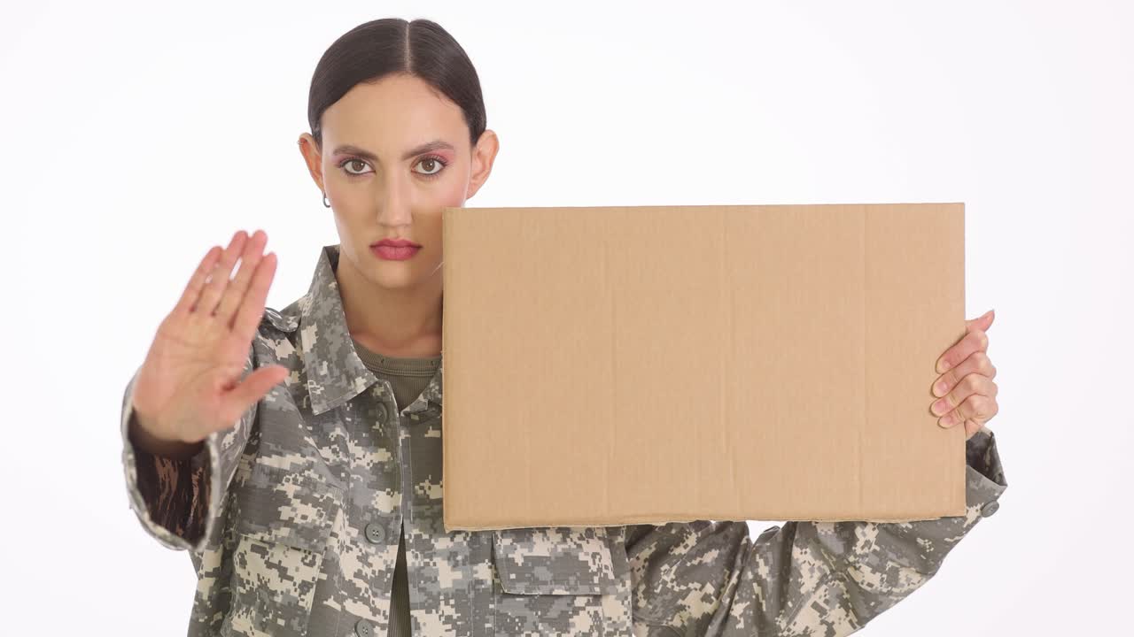 Woman in military uniform holding a blank sign and making a stop gesture
