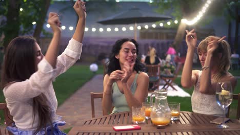 mujeres felices y emocionadas divirtiéndose y bailando en el restaurante al aire libre al atardecer