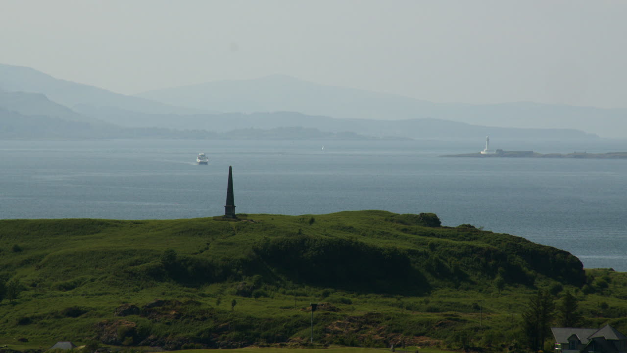 Long shot of Isle of Kerrera with Hutcheson's Monument and the Eilean Musdile lighthouse