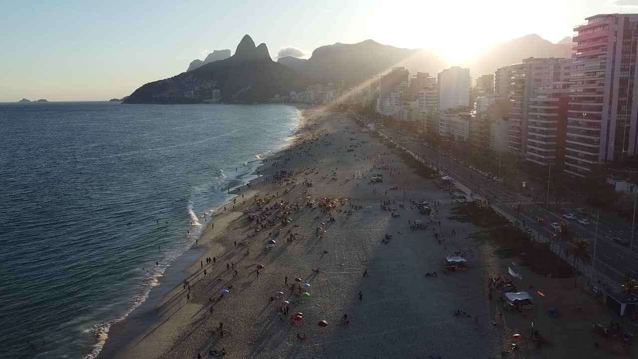 puesta de sol en la playa de arpoador en río de janeiro, momento de luz dorada por toma aérea de avión no tripulado, mar y montañas