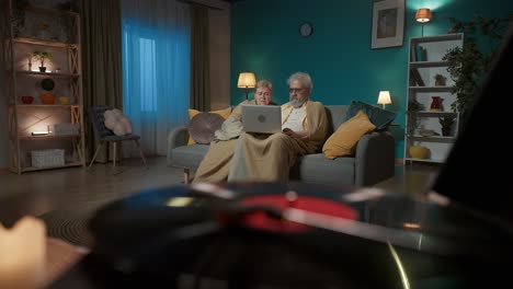 elderly couple using laptop at night