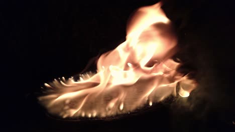 toma en cámara lenta de un tocón de brea que se quema y se alimenta de forma natural con su propio alquitrán en la noche oscura