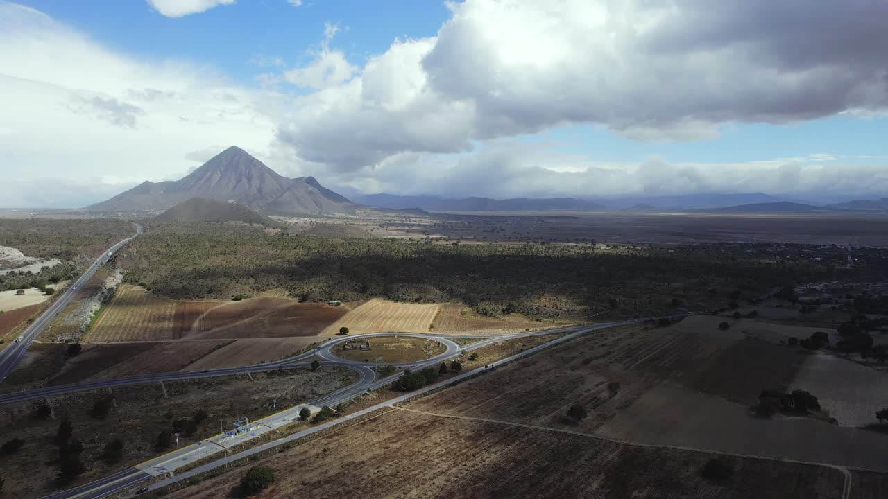 volando lentamente sobre una carretera mexicana con algunas nubes y una montaña en la espalda