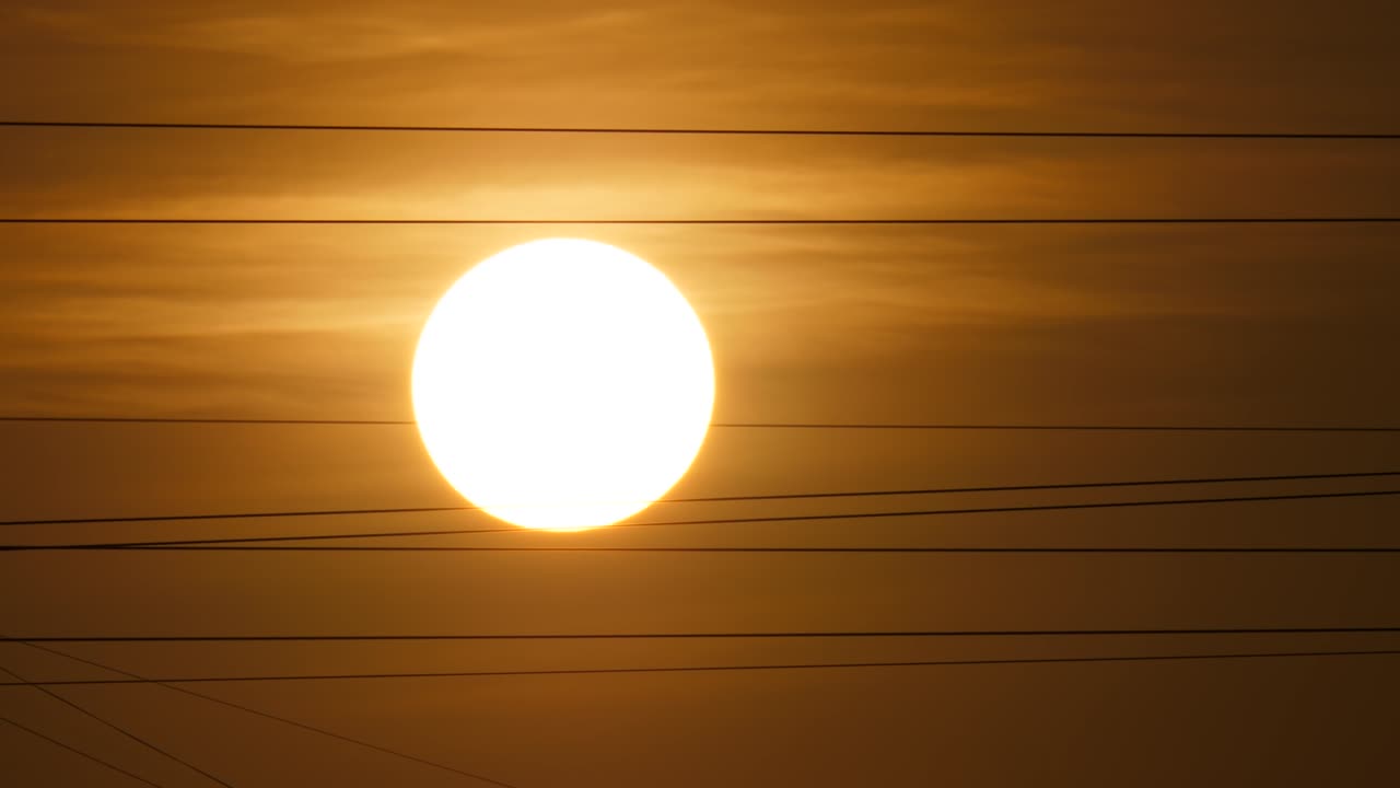 солнечный диск движется по небу, телеобъект, волоконные провода дрожат от ветра.