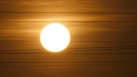 el disco solar se mueve a través del cielo, la vista telefoto, los cables de fibra óptica tiemblan con el viento