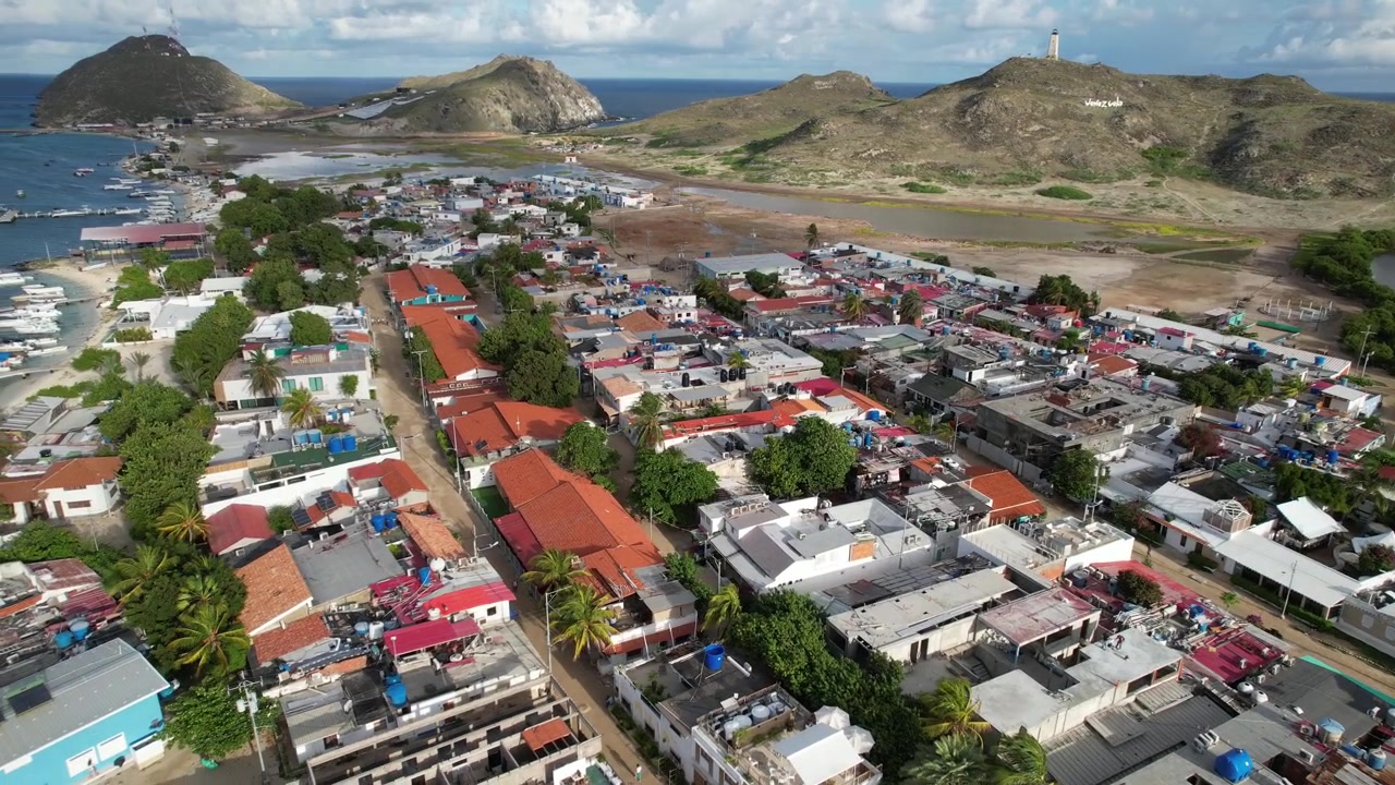 Vista aérea de un vibrante pueblo pesquero anidado entre colinas ondulantes y una costa serena