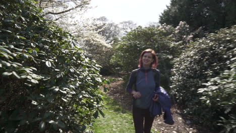 dolly shot of a girl walking through gardens in edinburgh and then stopping to smell a nice flower on a nice and sunny day