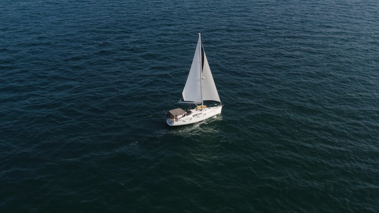 Barca a vela di lusso con due vele bianche veleggia placidamente nel vento sulle acque calme, limpide e increspate del Mar Mediterraneo in Israele