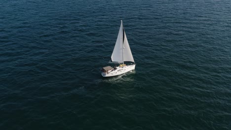 velero de lujo con dos velas blancas navega tranquilamente en el viento sobre las tranquilas aguas claras y onduladas del mar mediterráneo en israel