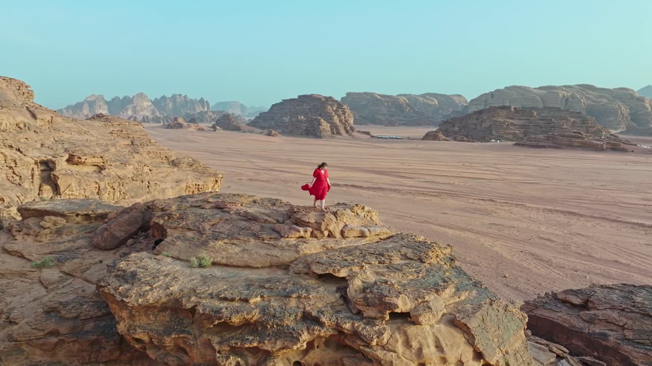Stigende opptak av en kvinne som står på naturlige sandsteinsklipper i Wadi Rum verneområde, Jordan