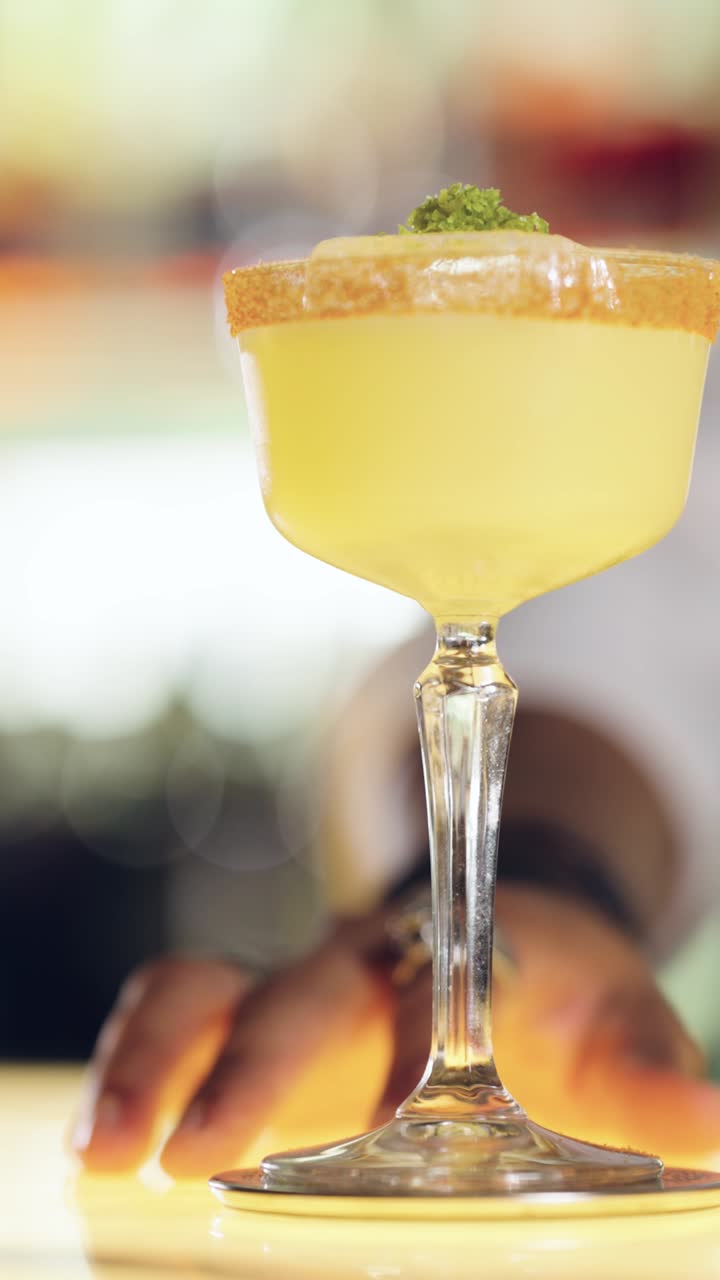 Elegante cóctel amarillo con guarnición servido por un barman