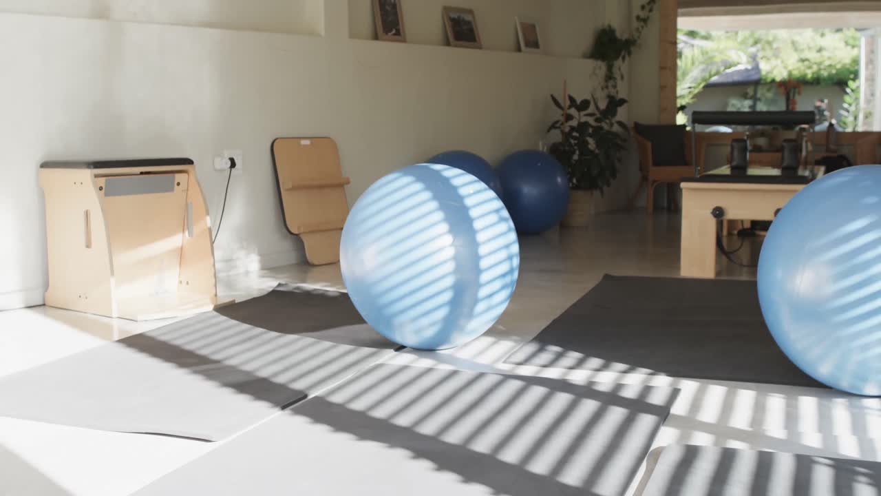 vista general de la sala de rehabilitación de pilates vacía con esteras de ejercicio y pelotas, cámara lenta