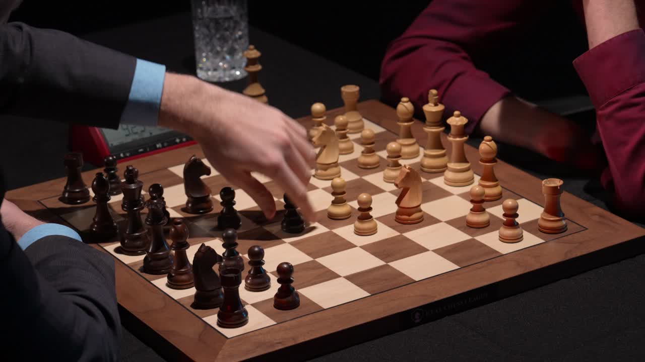 Chess opening moves on wooden board with two opponents and tournament clock running in the background