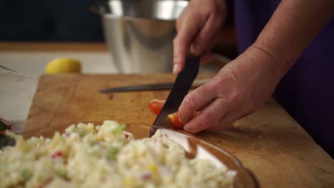 elder caucasian woman cuts cherry tomatoes for salad