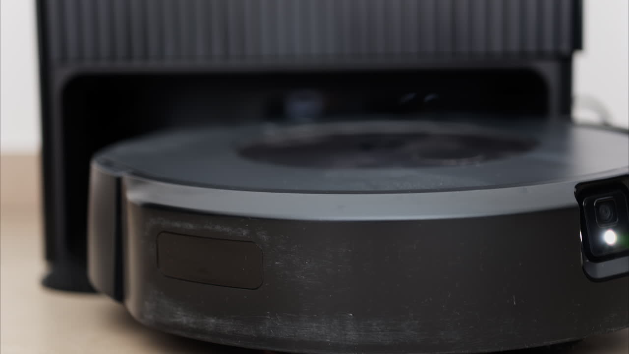 Close up of a black robot vacuum cleaner moving and rotating on the floor tiles
