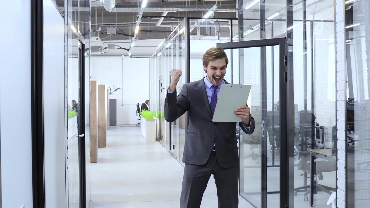 Empresario feliz celebrando el éxito mientras camina en una oficina moderna