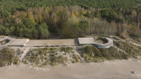 an aerial view of a defensive ww2 turret with preserved cannon on the coast of the baltic sea