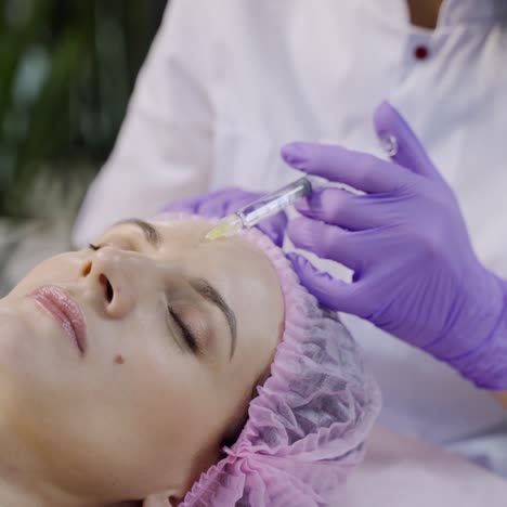 a beautiful woman is lying on a couch with at the cosmetologist on a mesotherapy procedure in the cosmetology. close-up
