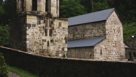 mtsvane monastery chapel and bell tower behind low stone wall, georgia