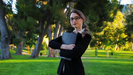 attractive caucasian business woman walks toward the camera, and looks at the camera with a smile and a laugh