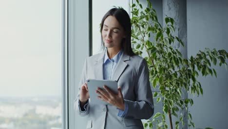 mujer de negocios usando la tableta junto a la ventana