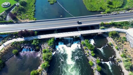 Drone aerial landscape of car vehicle transport driving over bridge running river stream in Bend Whitewater Park Deschutes River Oregon USA America travel tourism lake