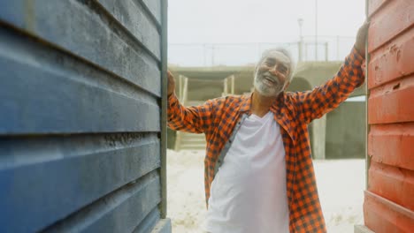 vista frontal de un hombre afroamericano mayor feliz y activo de pie en la cabaña de la playa en un día soleado 4k