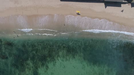 olas rompiendo y gente pasando en imágenes de drones de playa de agua cristalina