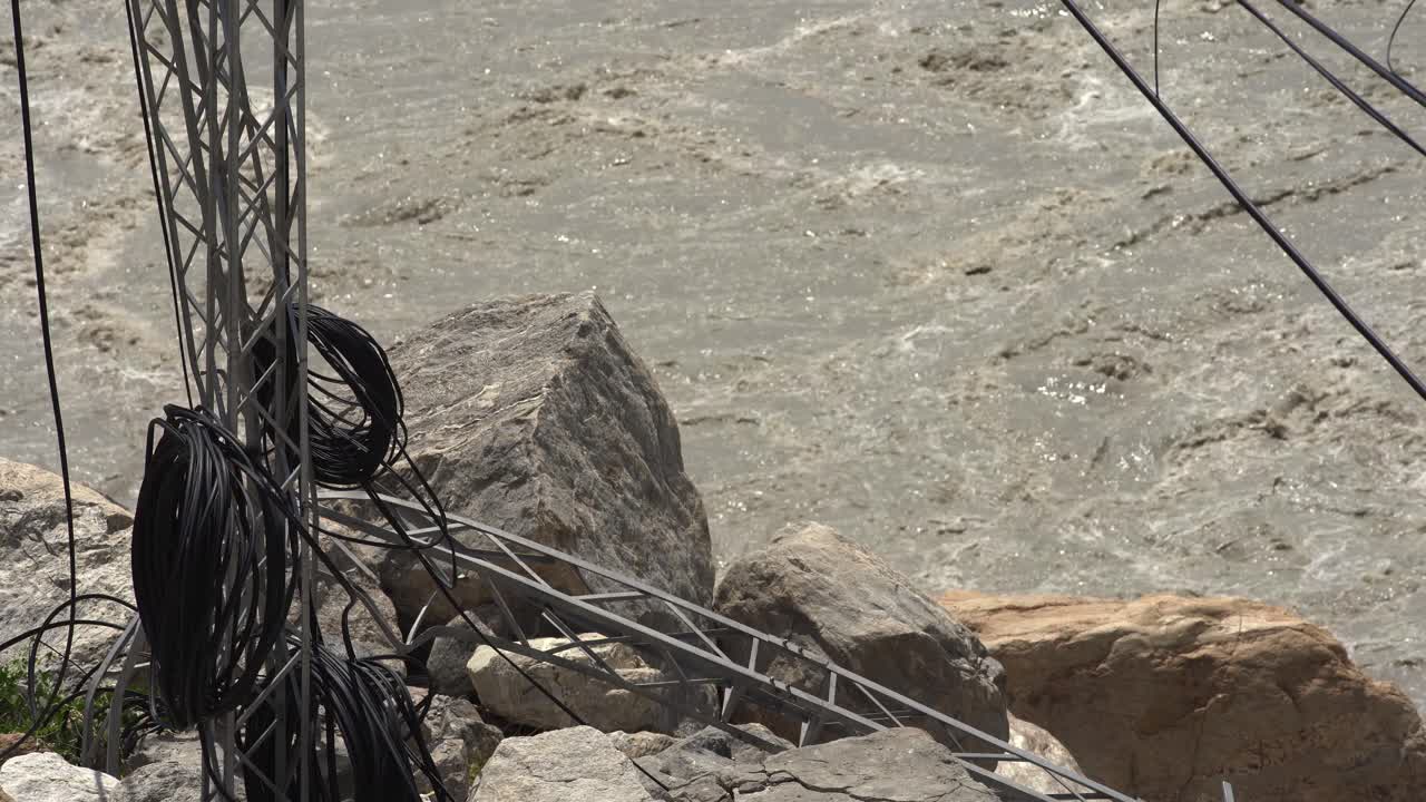 Damaged Electrical Tower Near Fast-Flowing River