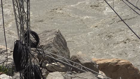 damaged electrical tower near fast-flowing river
