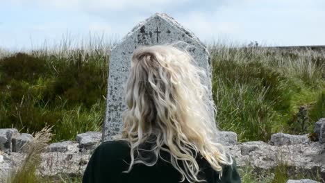 back of blond girl�s head staring at an old tumb stone