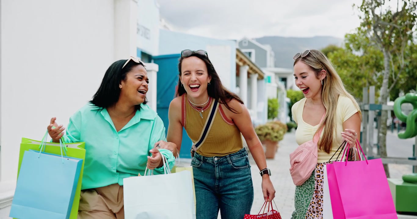 Tre amici felici che camminano ridendo con le buste della spesa