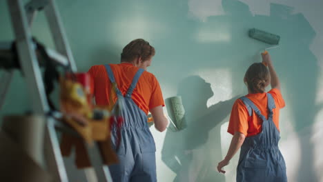 cheerful family painting together indoors. couple doing repair in new home.