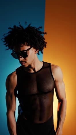stylish man with curly hair and sunglasses in dramatic dual-tone lighting